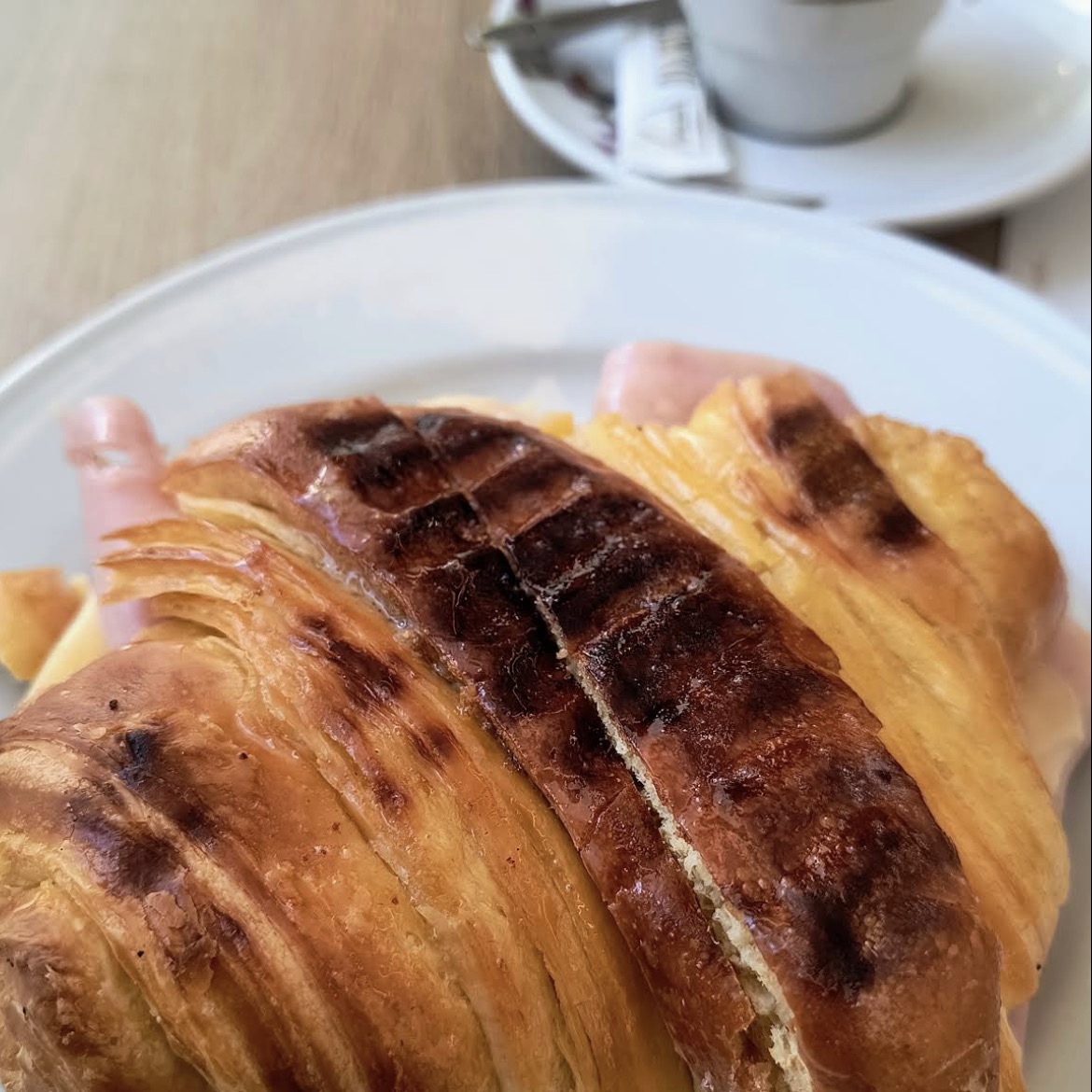 Croissant misto grelhado com um café